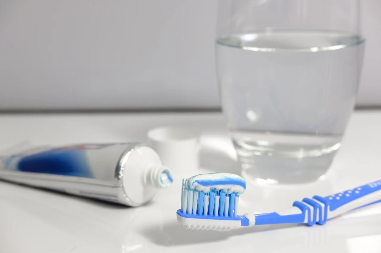 Close-up of daily dental hygiene items including a toothbrush, toothpaste, and a glass of water