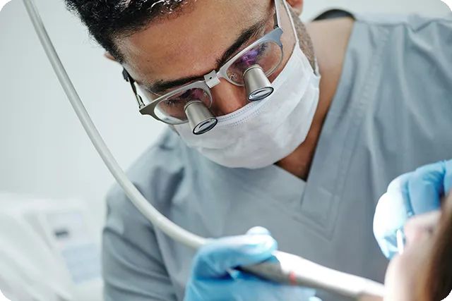 A professional dentist in a mask and surgical loupes performing an emergency procedure