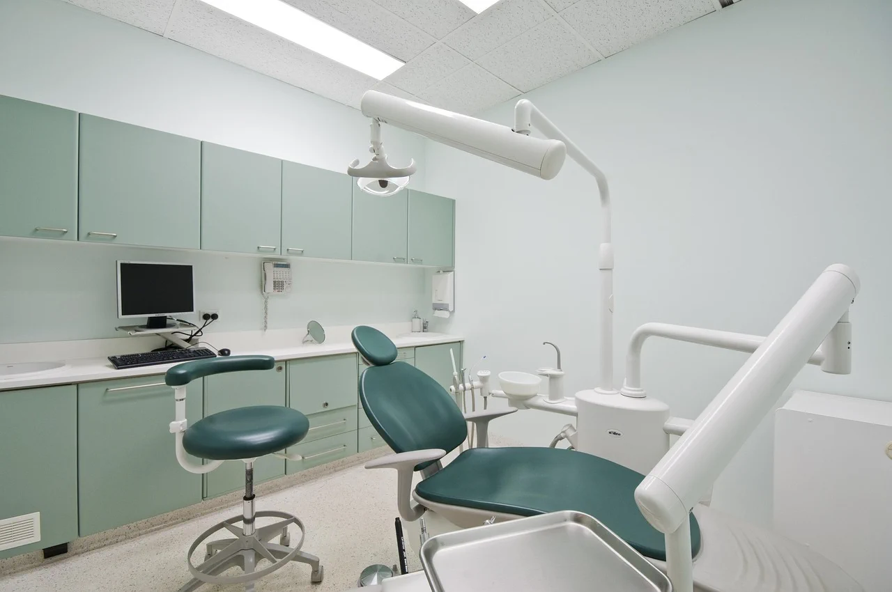 Dental treatment room featuring a dark green patient chair, medical cabinetry, and advanced clinical tools